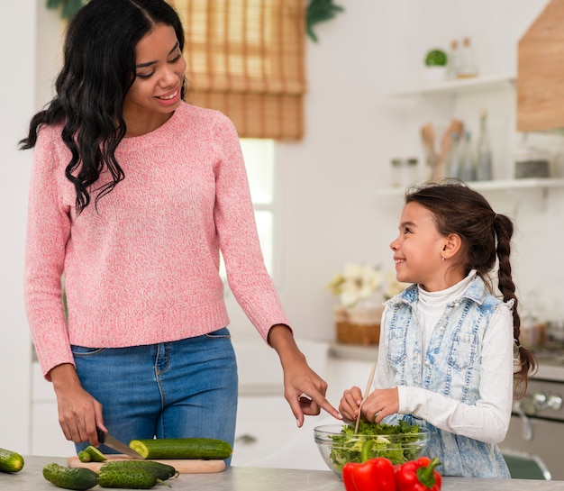 Bambina che impara a cucinare con la mamma