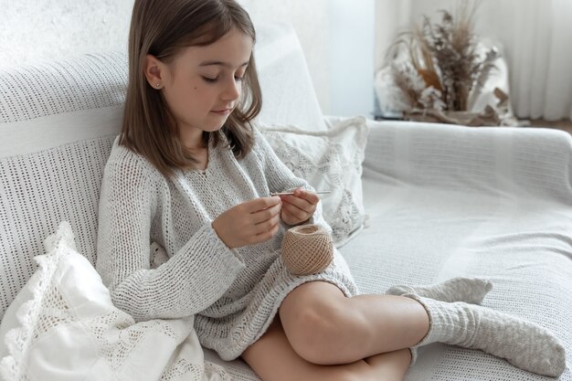 Bambina che impara a lavorare a maglia, a casa per il tempo libero e il concetto di ricamo.