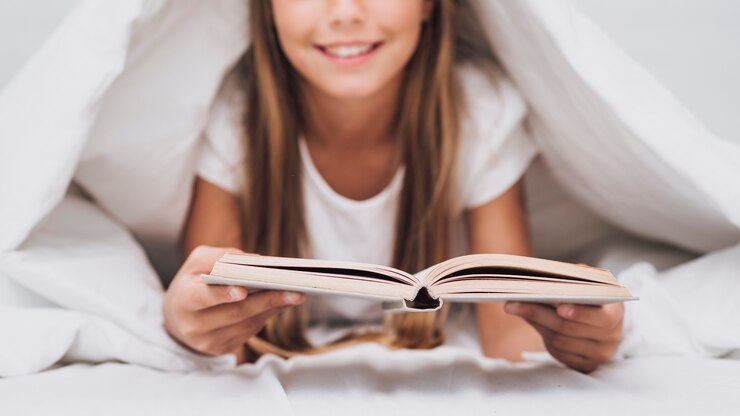 Foto gratuito bambina che legge un libro a letto