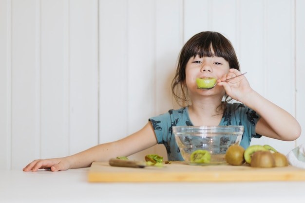 Bambina che mangia i kiwi