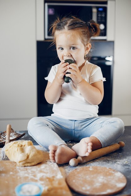 Bambina che mangia verdura su una tabella coperta di farina