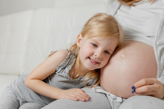Bambina che mette la sua testa vicino alla pancia della madre