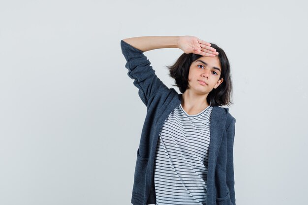 Bambina che mostra gesto di saluto in t-shirt, giacca e guardando fiducioso.