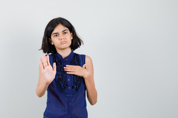Bambina che mostra il gesto di arresto in camicetta blu e guardando infastidito.