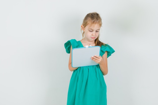 Bambina che scrive qualcosa a bordo nella vista frontale del vestito verde.