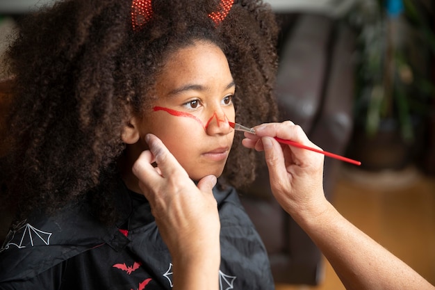 Bambina che si prepara per halloween con un costume da diavolo