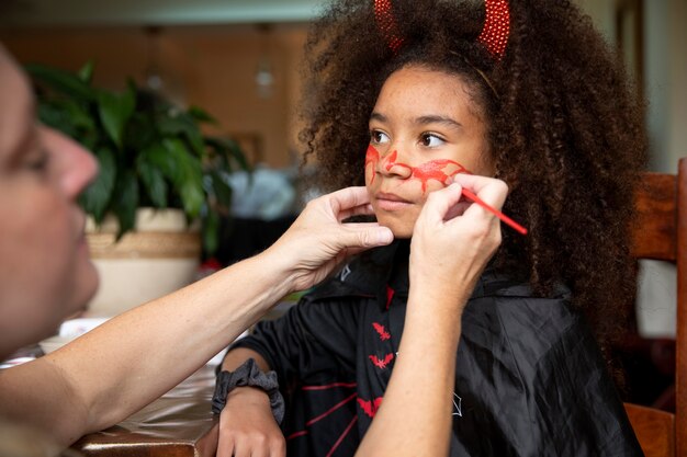 Bambina che si prepara per halloween con un costume da diavolo