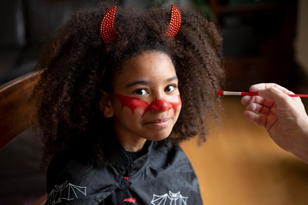 Bambina che si prepara per halloween con un costume da diavolo