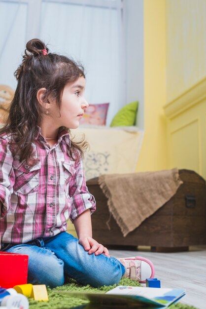 Bambina che si siede con i giocattoli