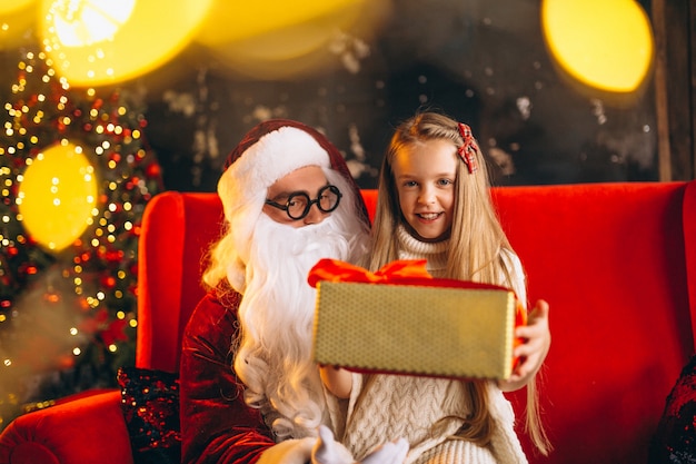 Bambina che si siede con santa e regali a Natale