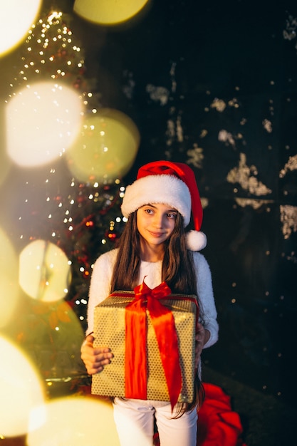 Bambina che si siede dall&#39;albero di Natale e regali di disimballaggio