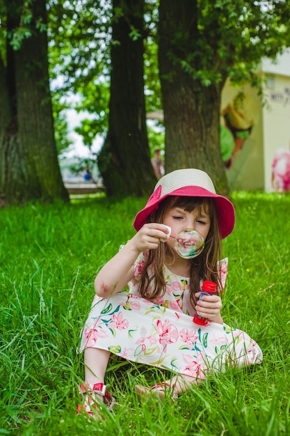 Bambina che si siede fare bolle di sapone