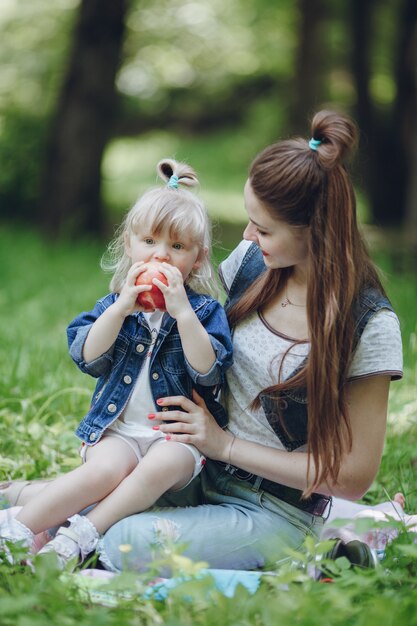 Bambina che si siede in cima alla sua madre che morde una mela