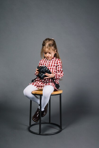Bambina che si siede sulle feci che guarda l&#39;obbiettivo su sfondo grigio
