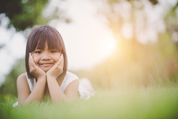 Bambina che si trova confortevolmente sull&#39;erba e sul sorridere