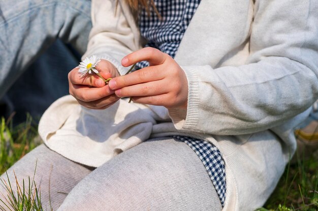 Bambina che tiene il fiore della margherita bianca