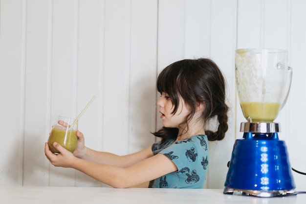 Bambina che tiene un bicchiere di frullato