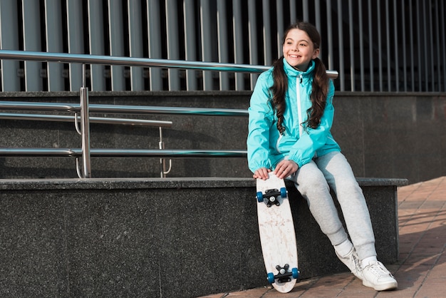 Bambina che tiene uno skateboard accanto a lei con lo spazio della copia