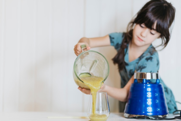 Bambina che versa frullato al vetro