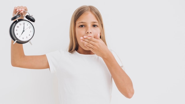 Bambina colpita che tiene un orologio in su