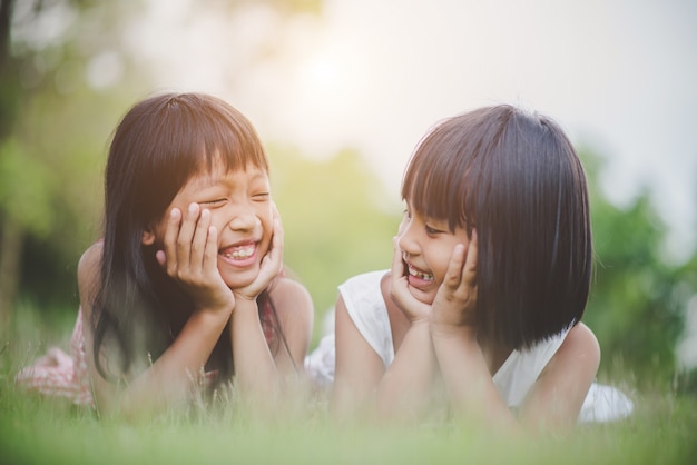 Bambina con amico sdraiato comodamente sull&#39;erba e sorridente