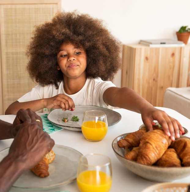 Bambina con capelli ricci che mangia prima colazione