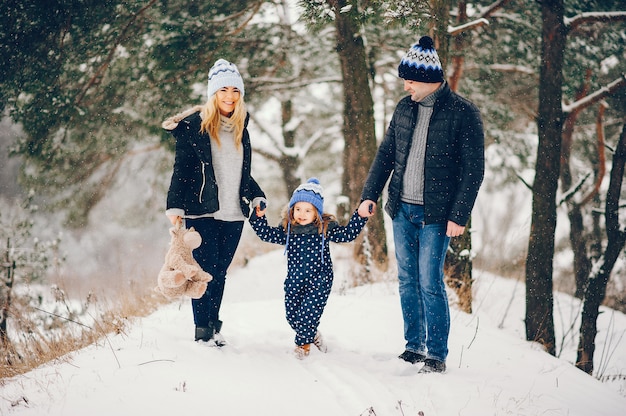 Bambina con i genitori che giocano in un parco d'inverno