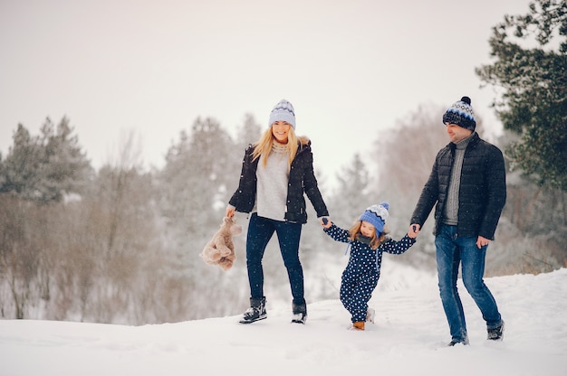 Bambina con i genitori che giocano in un parco d'inverno