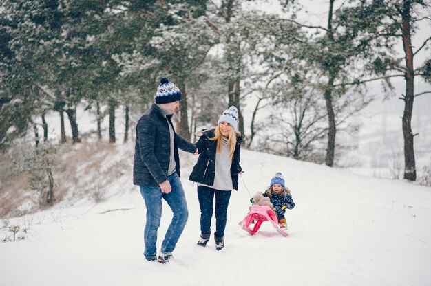 Bambina con i genitori che giocano in un parco d'inverno