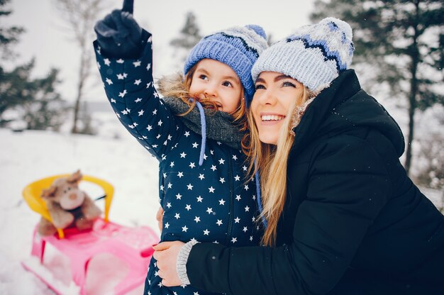 Bambina con la madre che gioca in un parco d'inverno