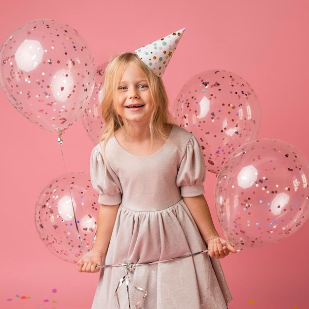 Bambina con palloncini e cappello da festa