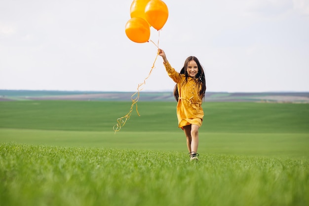 Bambina con palloncini gialli nel campo