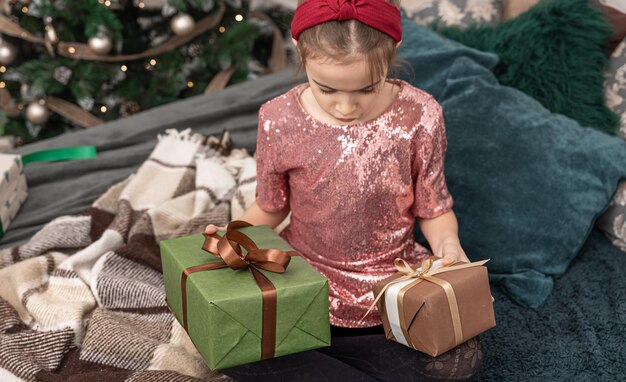 Bambina con scatole regalo di natale sul letto in camera