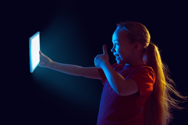 Bambina con tablet in luce al neon