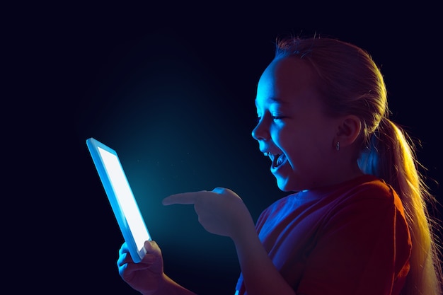 Bambina con tablet in luce al neon