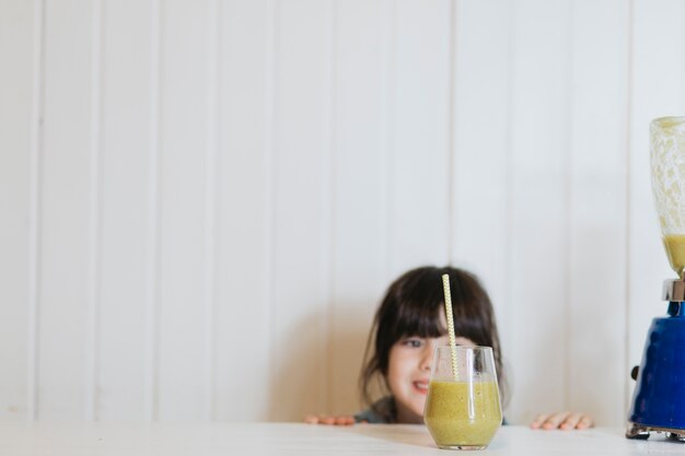 Bambina con un bicchiere di gustoso frullato