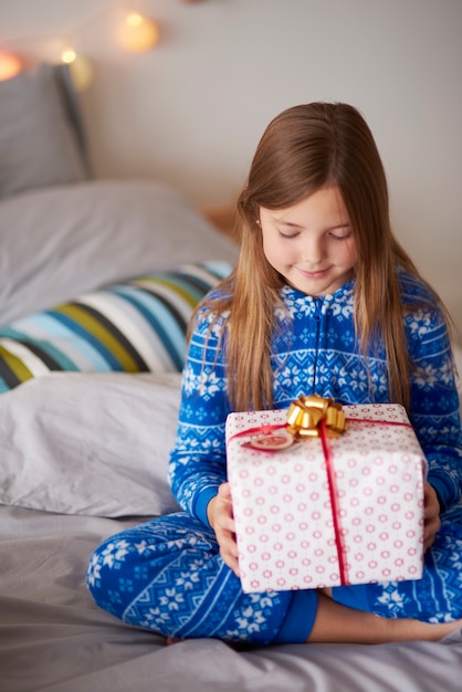 Bambina con un regalo di Natale nel letto