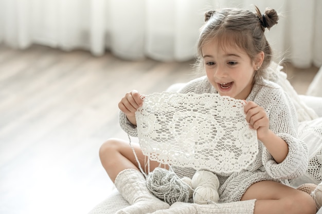 Bambina con un tovagliolo di pizzo di filato di cotone naturale, uncinetto a mano. Uncinetto come hobby.