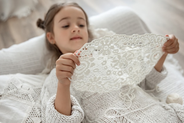 Bambina con un tovagliolo di pizzo di filato di cotone naturale, uncinetto a mano. Uncinetto come hobby.