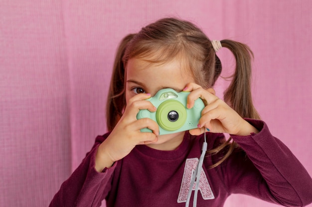 Bambina del ritratto che gioca con la macchina fotografica