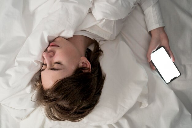 Bambina del ritratto usando il telefono mentre dorme