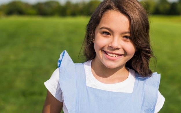 Bambina di smiley di vista frontale che esamina la macchina fotografica