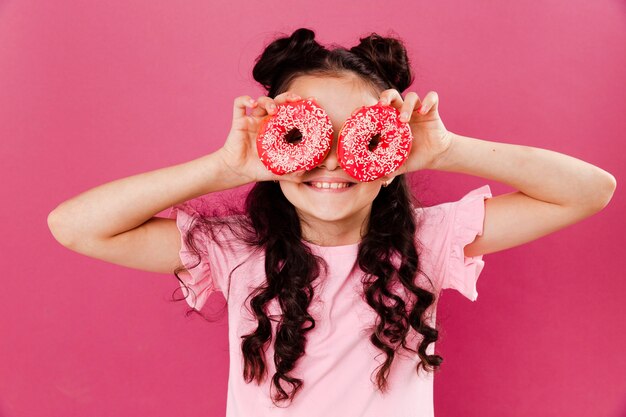 Bambina di vista frontale che gioca con il doughntus