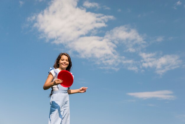 Bambina di vista frontale che gioca con il frisbee rosso