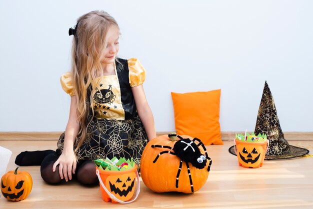 Bambina di vista frontale che si siede sul pavimento su Halloween