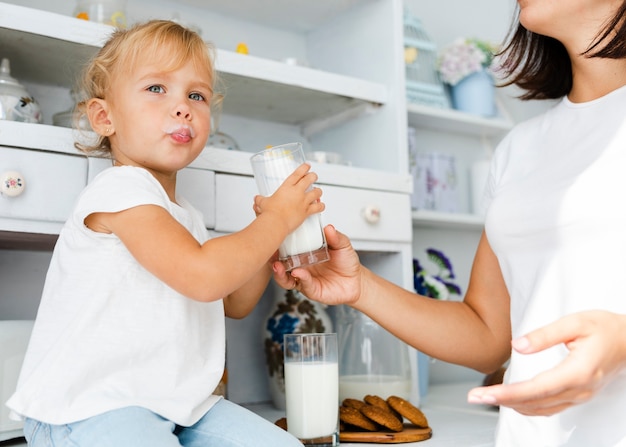 Bambina divertente che tiene un bicchiere di latte