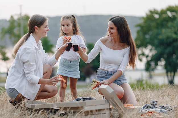 Bambina divertirsi al picnic, pizza, bevande, estate e prato