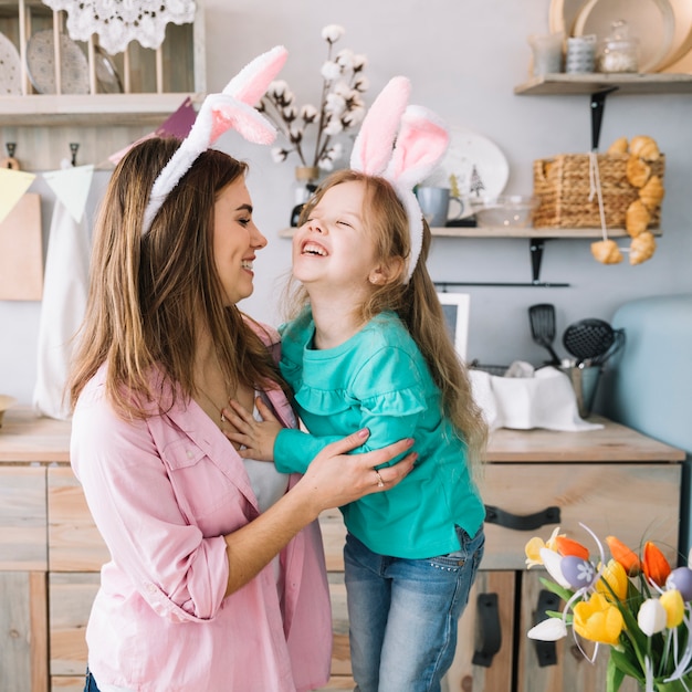 Bambina e madre nelle orecchie del coniglietto che ridono