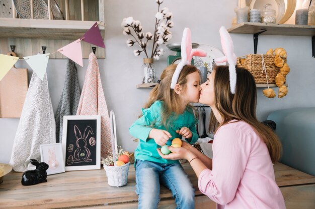 Bambina e madre nelle orecchie di coniglio baciare