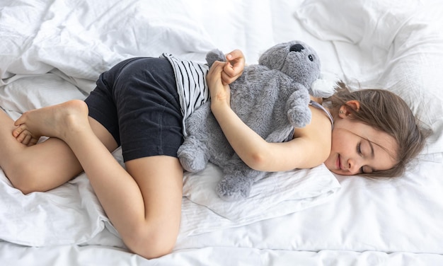 Bambina felice con il koala di peluche a letto